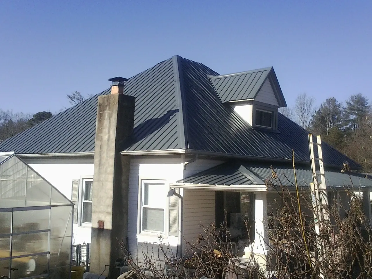 Dark blue standing seam metal roof on a white farmhouse with dormer — Slate & Tile Roof Repair by Roofing Brothers in Eagleville