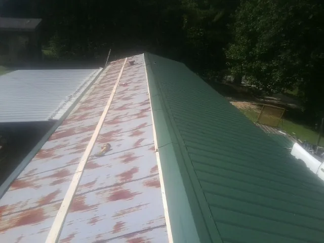 Old rusted panels beside newly installed green metal roofing — Wind Damage Roof Repair by Roofing Brothers in Eagleville