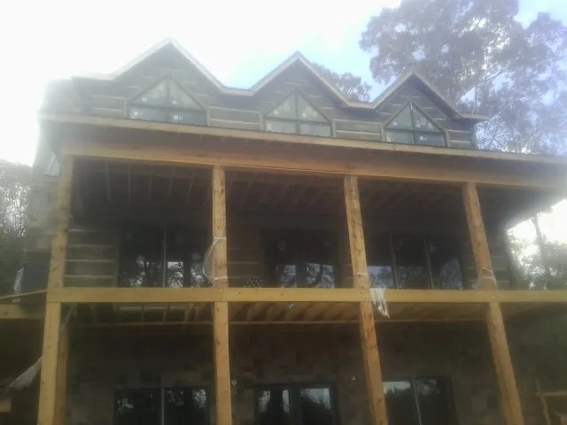 Dormers and porch framing on a large log home under construction — Roof Coating work by our crew in Eagleville