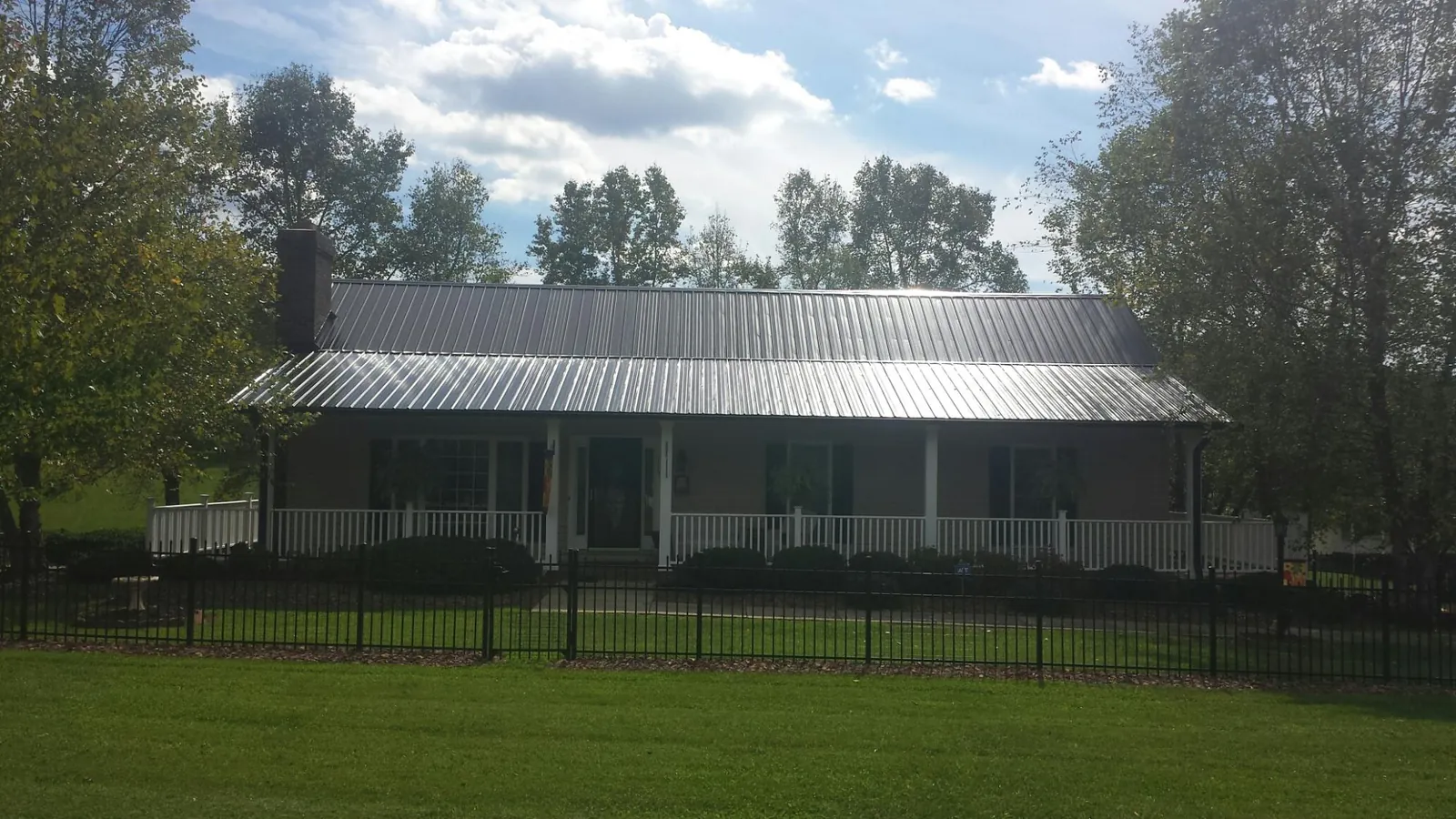 Gray metal roof on a brick ranch with a full width front porch — Gutter Guard Installation work by our crew in Eagleville