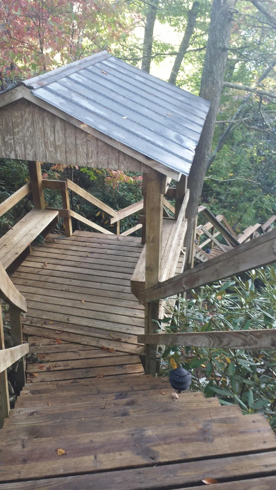 Metal roofed shelter over wooden steps on a wooded walkway — Skylight Repair & Installation work by our crew in Eagleville