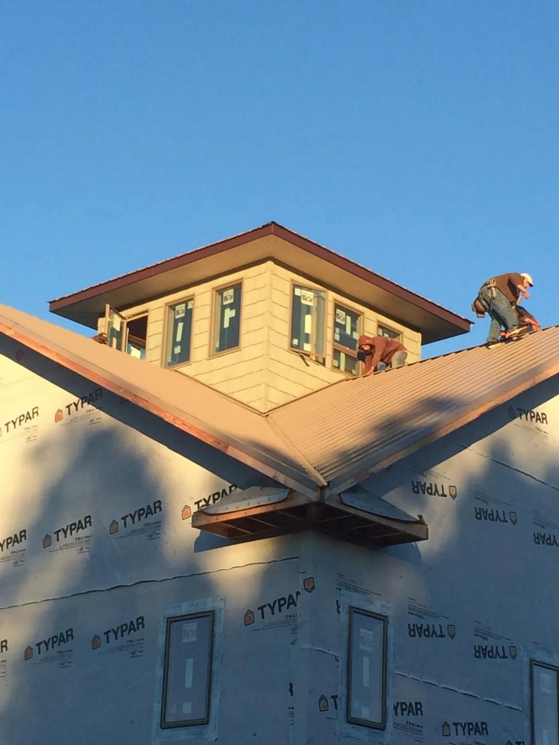 Roofers working around a rooftop cupola on a new metal roof at sunset — Roof Waterproofing in Eagleville by Roofing Brothers